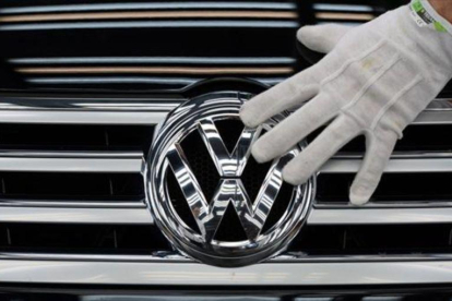 Un empleado coloca el logotipo de Volkswagen a un vehículo.
