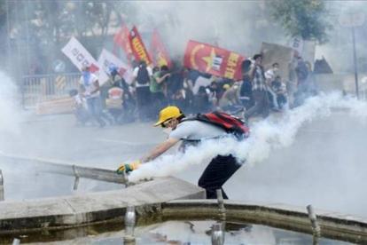 Un manifestante intenta sujetar una bomba lacrimógena, este domingo en Ankara.