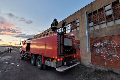 Un vehículo de los bomberos junto a la nave abandonada que ayer se incendió en Villabalter. BOMBEROS DE LEÓN