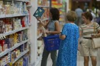 Tres mujeres contemplan los productos y los precios en un supermercado de León