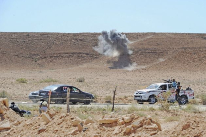 Un cohete lanzado por los leales a Gadafi explota lejos de un vehículo rebelde al norte de la ciudad de Bani Walid en Libia.