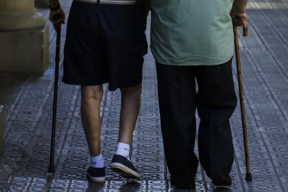 Dos ancianos pasean por una calle.