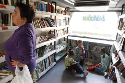 Imagen de una mujer y tres niños en uno de los bibliobuses en la localidad leonesa de Villaquejida.