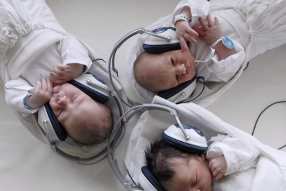 Bebés recién nacidos escuchan música con auriculares en un hogar maternal.