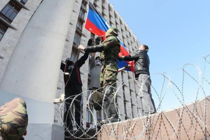 Manifestantes prorrusos izan la bandera de la autodenominada República de Donetsk, en la sede del Gobierno local, este lunes.
