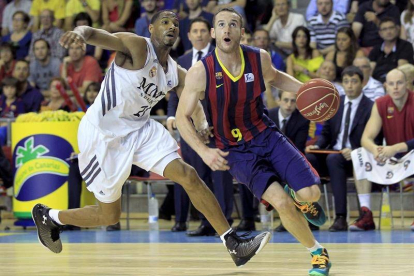 El base brasileño del FC Barcelona Marcelinho Huertas (d) avanza ante la defensa del alero estadounidense del Real Madrid Tremmell Darden (i), durante el tercer partido del Play Off por el título de la Liga ACB jugado esta tarde en el Palau Blaugrana de B