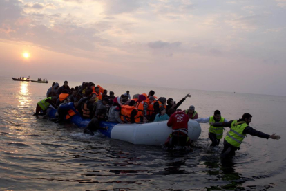 Varios voluntarios ayudan a un grupo de refugiaos a llegar a la costa, en la isla griega de Lesbos, el pasado marzo.