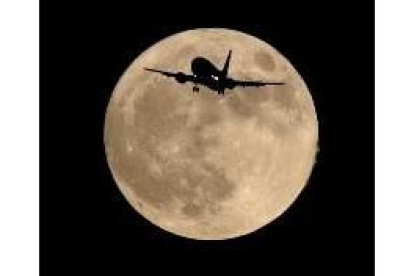 La imagen muestra la silueta de un avión en vuelo sobre una luna llena