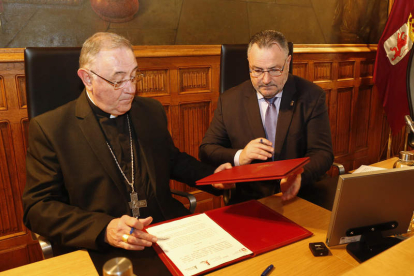 Ángel de las Heras, obispo de León, y Eduardo Morán, presidente de la Diputación, ayer, en la firma del convenio. FERNANDO OTERO