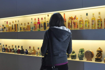 Una mujer observa botellas de tequila en México. SÁSHENKA GUTIÉRREZ