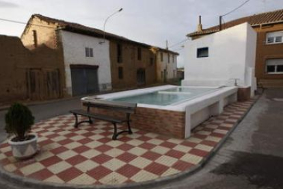 La imagen muestra una plaza de Vega de Infanzones en la que se encuentra un lavadero.