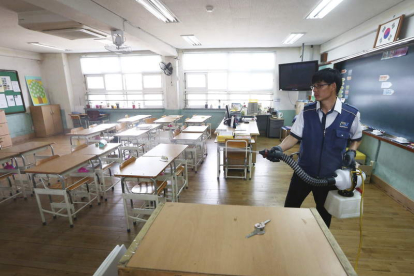 Un empleado desinfecta un aula de una escuela primaria de Seúl.