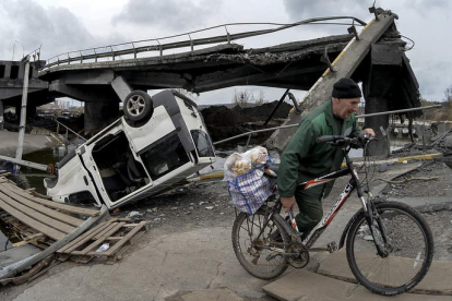Un hombre con una bicicleta
cruza el puente destruido a
las fueras de la ciudad
reconquistada de Irpin. ANDRII
NESTERENKO