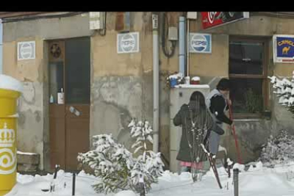 Una mujer limpia la entrada a su establecimiento, en el barrio de Cantamilanos ubicado en las afueras de León