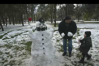 Un padre hace un muñeco de nieve con su hijo, en la ciudad de Ponferrada, cuyos vecinos vieron también la nieve estos días