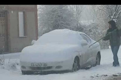 Una mujer se afana en retirar toda la nieve acumulada en su vehículo