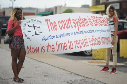 Dos jóvenes protestan en Ferguson con una pancarta contra el sistema judicial estadounidense.
