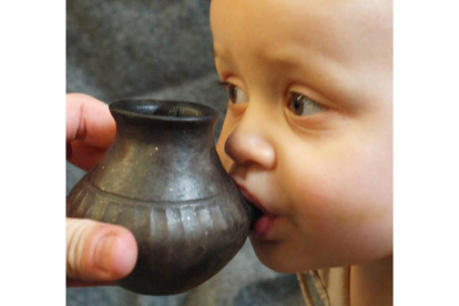 Un niño bebe agua en un biberón de arcilla como los usados en el Neolítico. NATURE