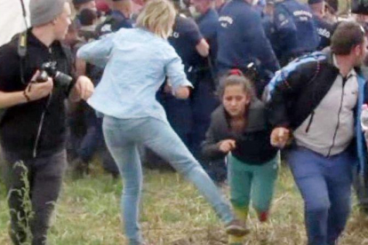 Imagen de un video en la que se ve a la reportera Petra László como hace la zancadilla a una niña refugiada que huye de la policía en el campo de Roszke.