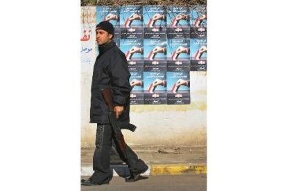 Un guardia pasa por delante de los carteles electorales en Bagdad