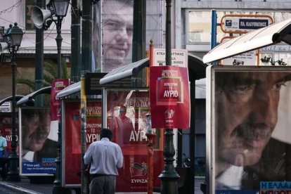 Un hombre pasa junto a un cartel electoral de Meïmarakis (derecha) y otro de Tsipras (arriba), este miércoles en Atenas.