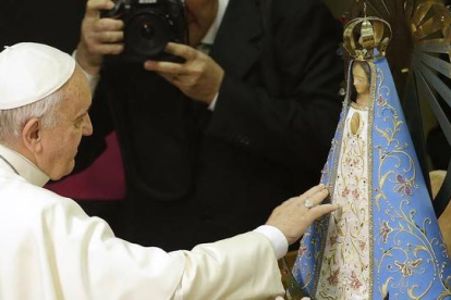 El Papa Francisco toca una estatua de la Virgen María durante una ceremonia en el Vaticano este jueves.