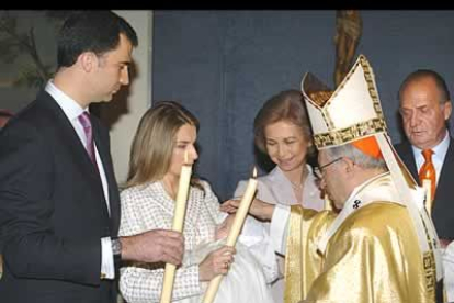 Otro momento del bautizo con los Príncipes de Asturias sosteniendo las velas.