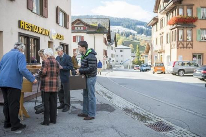 Residentes en la población suiza de Obersaxen Meierhof depositan su voto en urnas colocadas en el exterior de un colegio electoral, este domingo.
