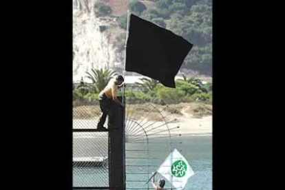 Algunos miembros de la asociación <b>Ecologistas en Acción</b> colocan una bandera negra como protesta en la verja que sirve como límite entre las aguas españolas y gibraltareñas.