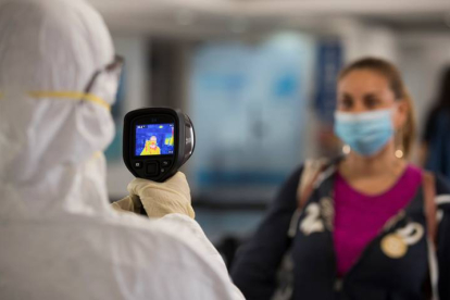 Personal de sanidad controla este martes la temperatura de los viajeros ante la pandemia del coronavirus. ORLANDO BARRIA