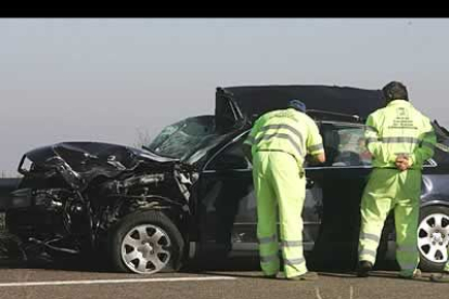 Dos miembros de la cuadrilla de la Red de Conservación de Carreteras del Estado, observan perplejos el estado en el que quedó el Audi en el que viajan las víctimas.