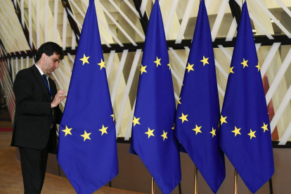 Un funcionario prepara las banderas de la Unión Europea antes del inicio de la cumbre, este domingo en Bruselas.