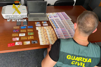 Un guardia civil recuenta el dinero, las tarjetas y el material localizados en el registro. GUARDIA CIVIL