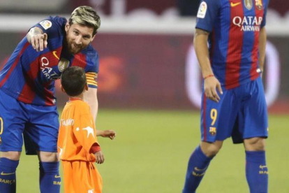 Messi indica a Murtaza, el niño afgano, que debe abandonar el césped en Doha.