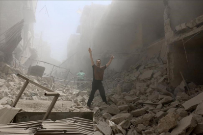 Un hombre pide ayuda en medio de los escombros de los edificios destruidos en una calle de Alepo.