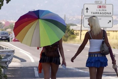 Dos chicas ejercen la prostitución en un carretera.