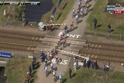 Parte del pelotón de la Paris-Roubaix, bloqueado en un paso a nivel.