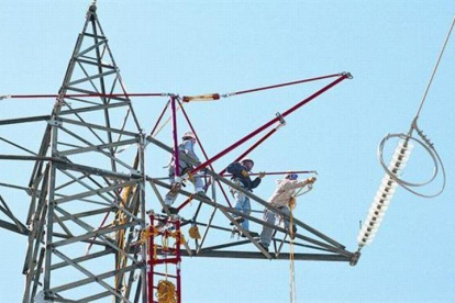 Un grupo de trabajadores preparan la sustitución del tendido de electricidad de una torre de alta tensión.