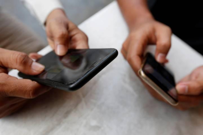 Dos adolescentes utilizan sus teléfonos móviles