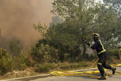 Dos efectivos del cuerpo de Bomberos durante las labores de extinción del incendio declarado en la zona de Es Cubells, en el municipio ibicenco de Sant Josep de sa Talaia.