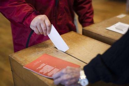 Un hombre votando si quiere limitar la entrada de los europeos al mercado laboral suizo.