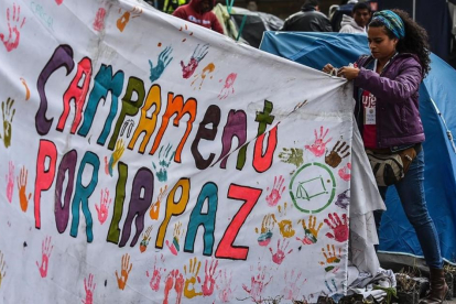Una joven ayuda a colocar una pancarta a favor del acuerdo de paz en la acampada de la plaza Bolivar, en Bogotá.