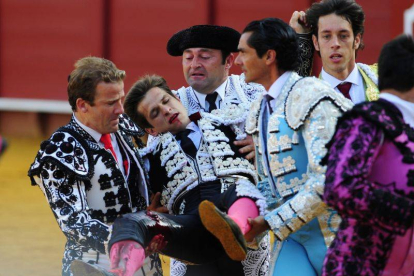 El diestro Julián López "El Juli" es sacado de la Real Maestranza de Sevilla por los matadores José María Manzanares (c) y Antonio Nazaré (d) y su cuadrilla, después de ser cogido por el primer toro de su lote.