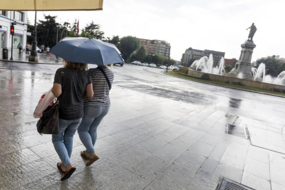 Dos mujeres se resguardan de la lluvia en León