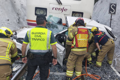 Los equipos de emergencias, tras el rescate de los cuerpos de los tres jóvenes que ocupaban el coche arrollado por un tren en el paso a nivel de Recimil. GUARDIA CIVIL