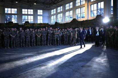 Macron entra ayer en un hangar en el que se encuentran las tropas francesas destacadas en el flanco este de la Otan. YOAN VALAT