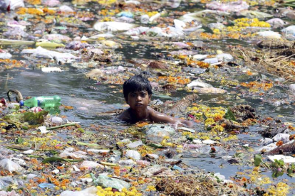 Un niño trapero nada entre plásticos en la India.