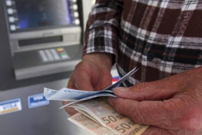 Un hombre saca dinero de un cajero automático. EFE