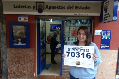 La lotera de Villamañán, Patricia Pellitero, con el cartel que anuncia el premio repartido. ARMANDO MEDINA