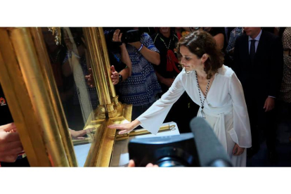Isabel Díaz Ayuso toca el cuadro de la Virgen de la Paloma ayer, en Madrid. FERNANDO ALVARADO